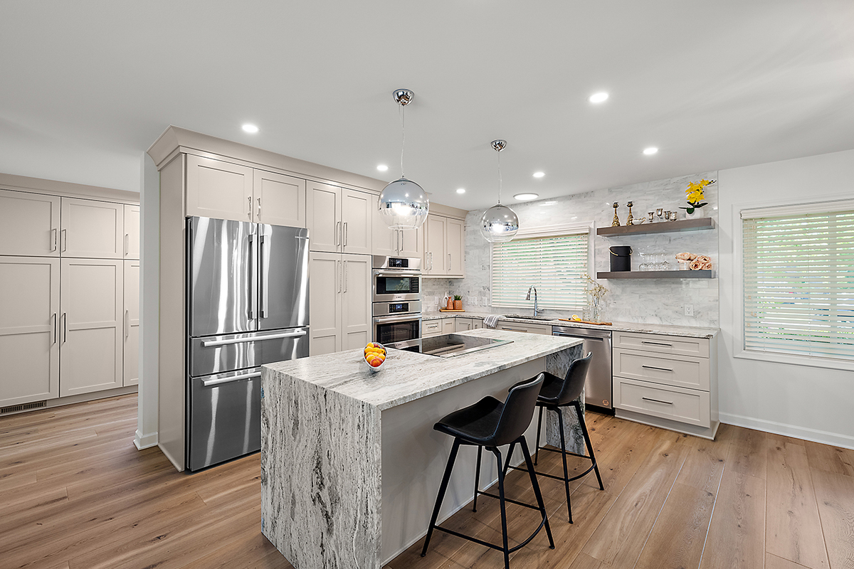 Light Mocha painted kitchen cabinets with an island that includes a beautiful waterfall granite countertop.