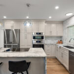 Light Mocha painted kitchen cabinets with an island that includes a beautiful waterfall granite countertop.