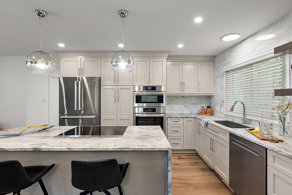 Light Mocha painted kitchen cabinets with an island that includes a beautiful waterfall granite countertop.