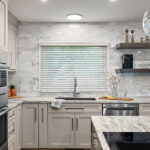 Light Mocha painted kitchen cabinets with an island that includes a beautiful waterfall granite countertop.