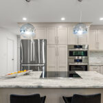 Light Mocha painted kitchen cabinets with an island that includes a beautiful waterfall granite countertop.