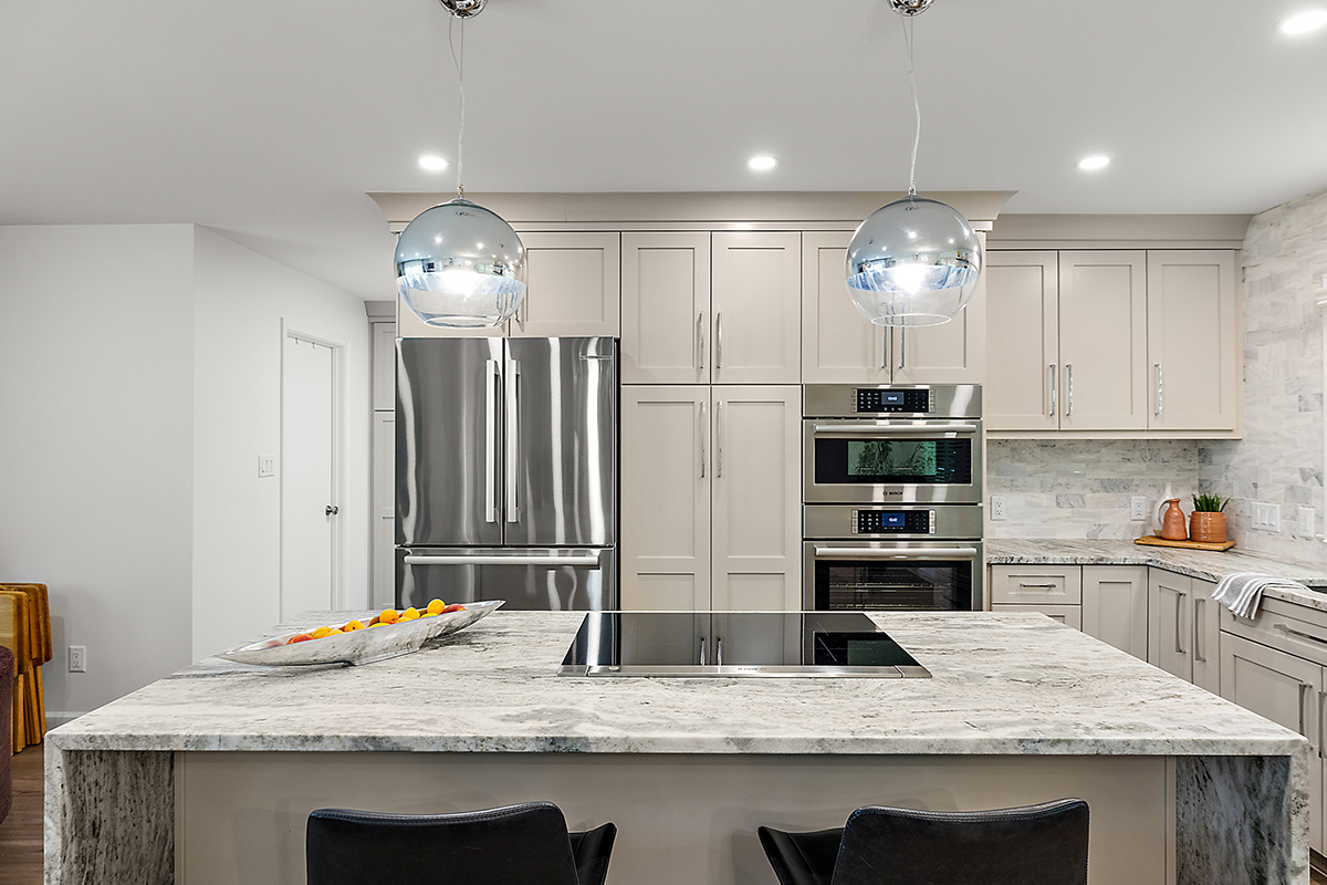Light Mocha painted kitchen cabinets with an island that includes a beautiful waterfall granite countertop.