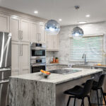 Light Mocha painted kitchen cabinets with an island that includes a beautiful waterfall granite countertop.