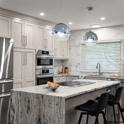 Light Mocha painted kitchen cabinets with an island that includes a beautiful waterfall granite countertop.