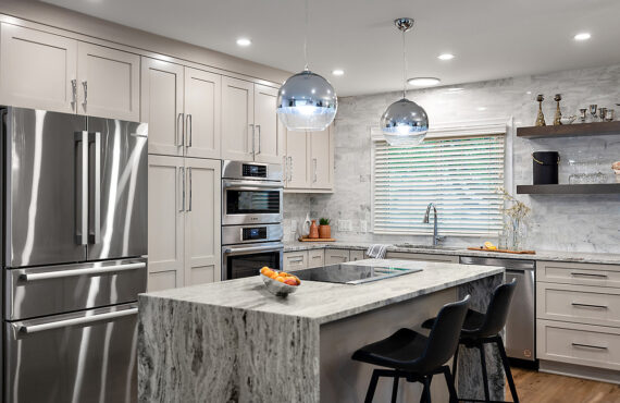 Light Mocha painted kitchen cabinets with an island that includes a beautiful waterfall granite countertop.