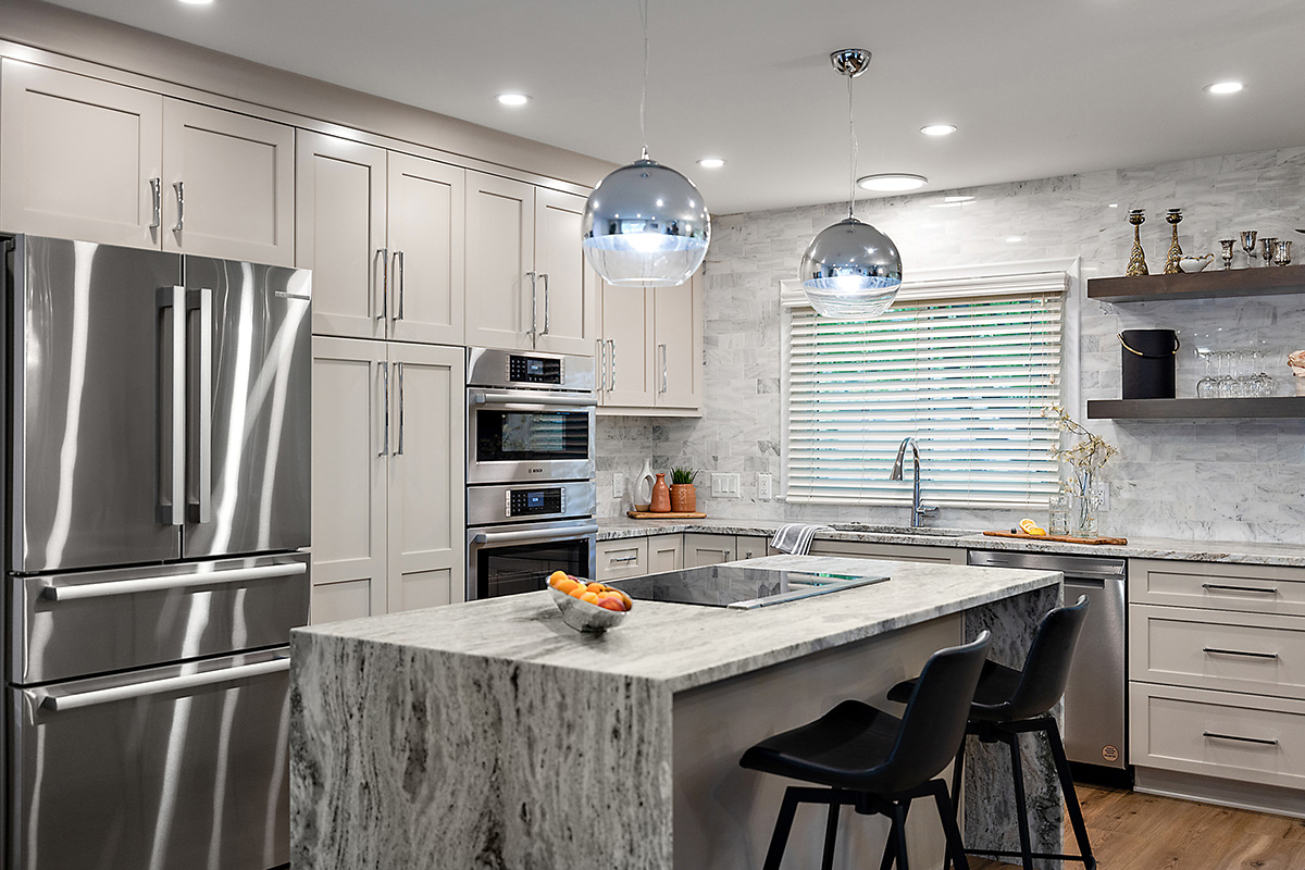 Light Mocha painted kitchen cabinets with an island that includes a beautiful waterfall granite countertop.