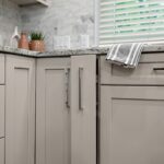 Light Mocha painted kitchen cabinets with an island that includes a beautiful waterfall granite countertop.
