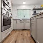 Light Mocha painted kitchen cabinets with an island that includes a beautiful waterfall granite countertop.
