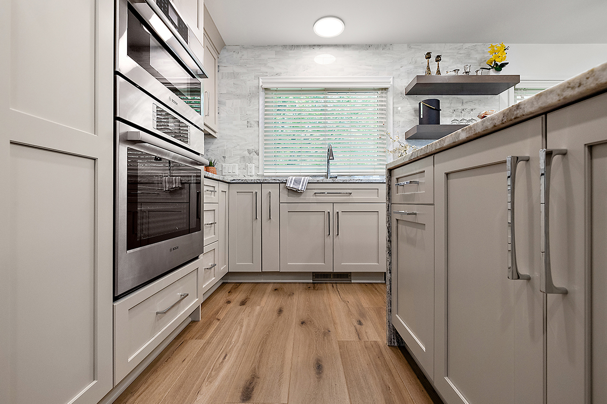 Light Mocha painted kitchen cabinets with an island that includes a beautiful waterfall granite countertop.