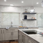 Light Mocha painted kitchen cabinets with an island that includes a beautiful waterfall granite countertop.