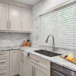 Light Mocha painted kitchen cabinets with an island that includes a beautiful waterfall granite countertop.