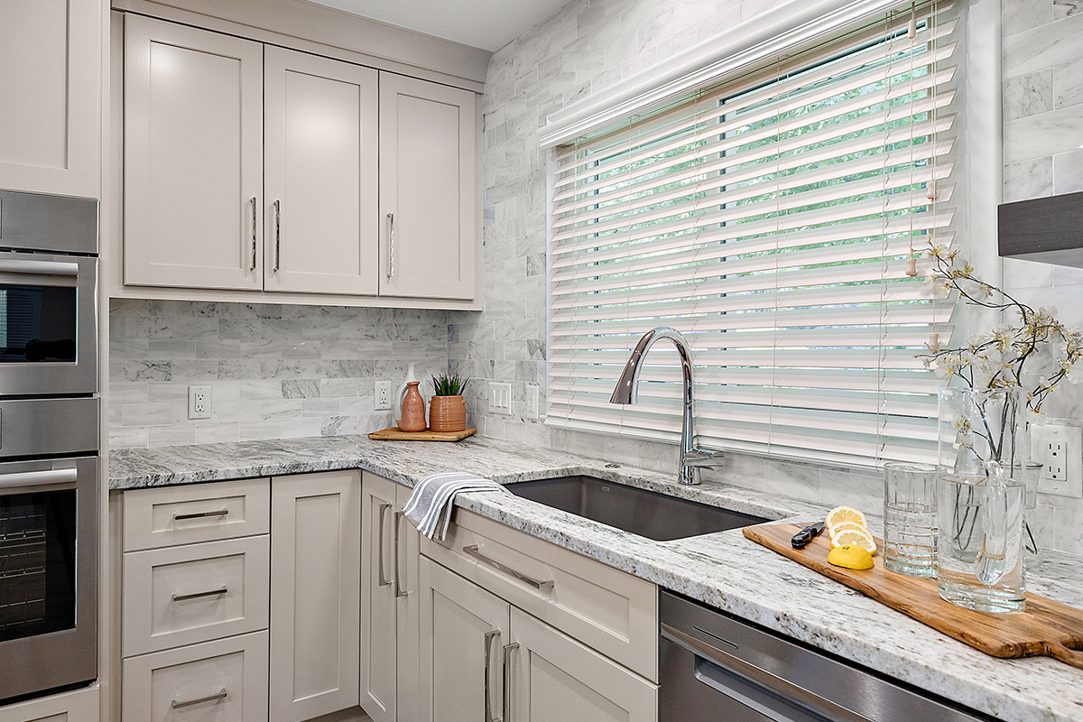 Light Mocha painted kitchen cabinets with an island that includes a beautiful waterfall granite countertop.