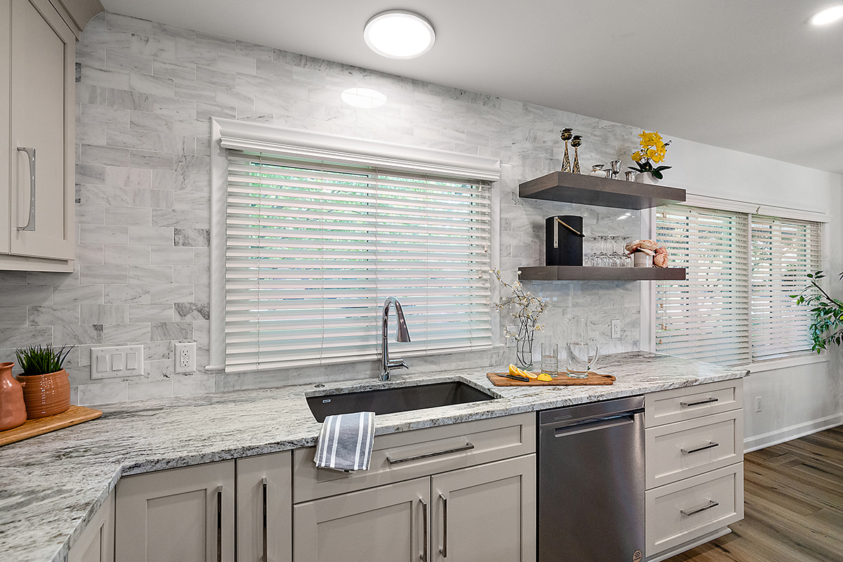 Light Mocha painted kitchen cabinets with an island that includes a beautiful waterfall granite countertop.