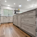 Light Mocha painted kitchen cabinets with an island that includes a beautiful waterfall granite countertop.
