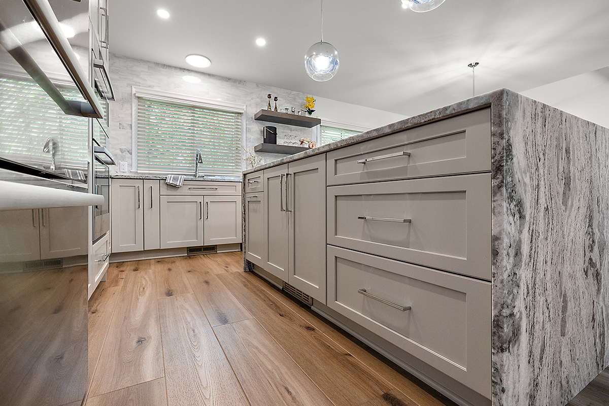 Light Mocha painted kitchen cabinets with an island that includes a beautiful waterfall granite countertop.
