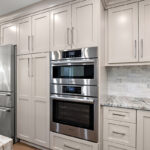 Light Mocha painted kitchen cabinets with an island that includes a beautiful waterfall granite countertop.
