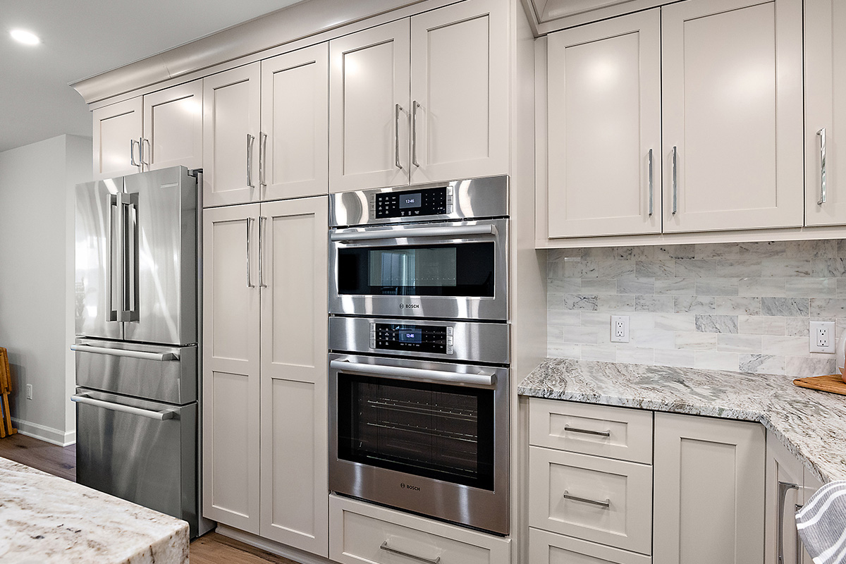 Light Mocha painted kitchen cabinets with an island that includes a beautiful waterfall granite countertop.
