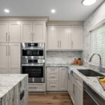 Light Mocha painted kitchen cabinets with an island that includes a beautiful waterfall granite countertop.