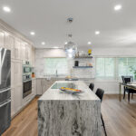 Light Mocha painted kitchen cabinets with an island that includes a beautiful waterfall granite countertop.