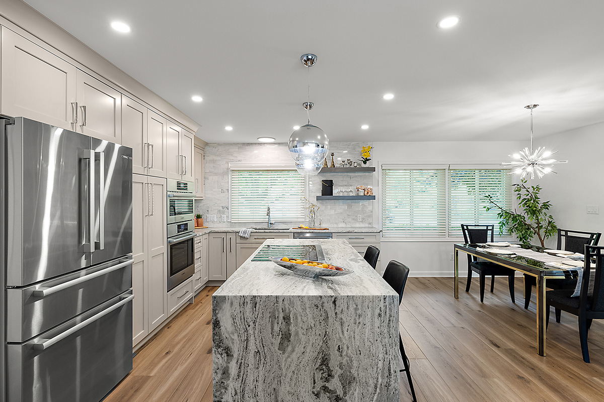 Light Mocha painted kitchen cabinets with an island that includes a beautiful waterfall granite countertop.