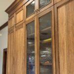 Stained kitchen cabinet. Photo shows detail of the applied molding Savannah door style and glass inserts in 4 doors on a stacked wall cabinet.