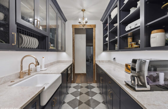View of long pantry space with dark painted cabinets