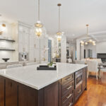 White painted kitchen perimeter cabinets with stained curved wood hood and island.