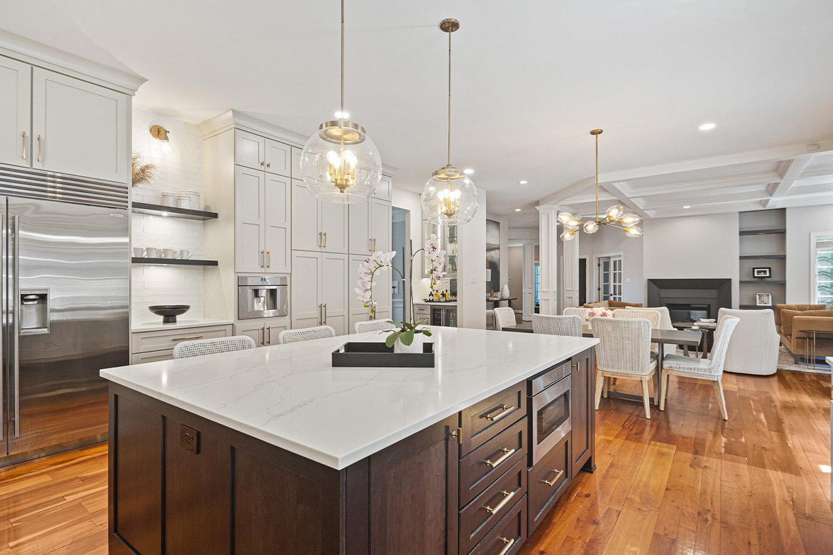 White painted kitchen perimeter cabinets with stained curved wood hood and island.