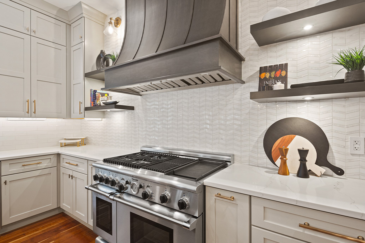 White painted kitchen perimeter cabinets with stained curved wood hood and island.
