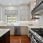 View of a window surrounded by white and stained kitchen cabinets with stainless steel oven.