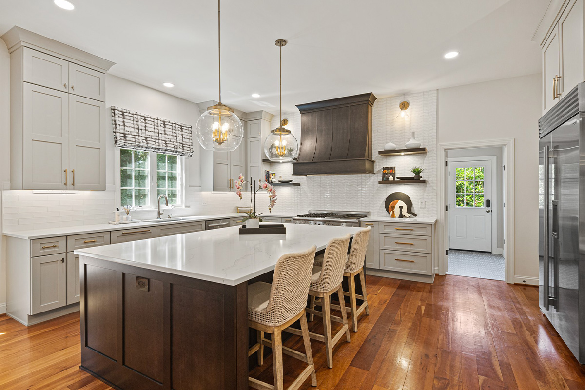 White painted kitchen perimeter cabinets with stained curved wood hood and island.