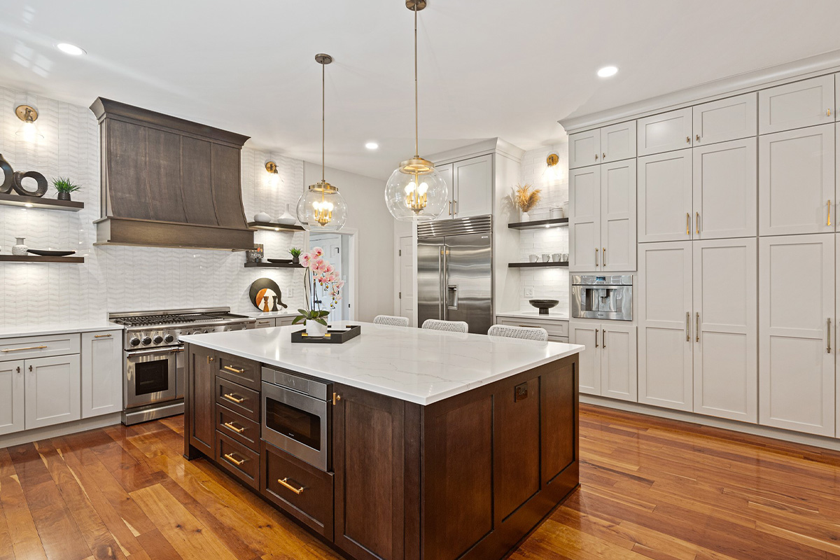 White painted kitchen perimeter cabinets with stained curved wood hood and island.