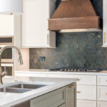 White painted kitchen perimeter with stained wood hood and gray painted island