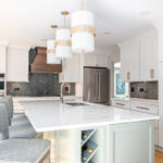 White painted kitchen perimeter with stained wood hood and gray painted island