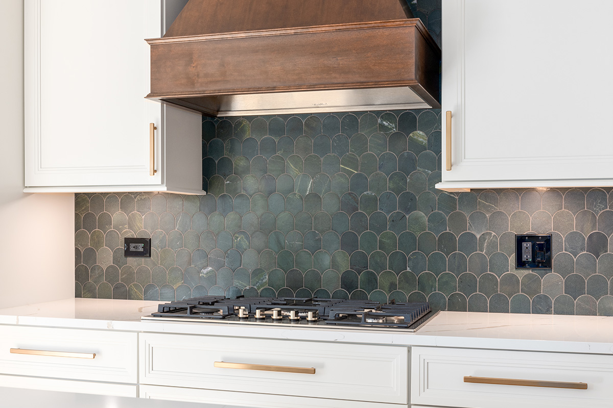 White painted kitchen perimeter with stained wood hood and gray painted island