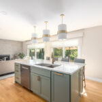 Gray painted kitchen island looking towards a living room with couch and fireplace