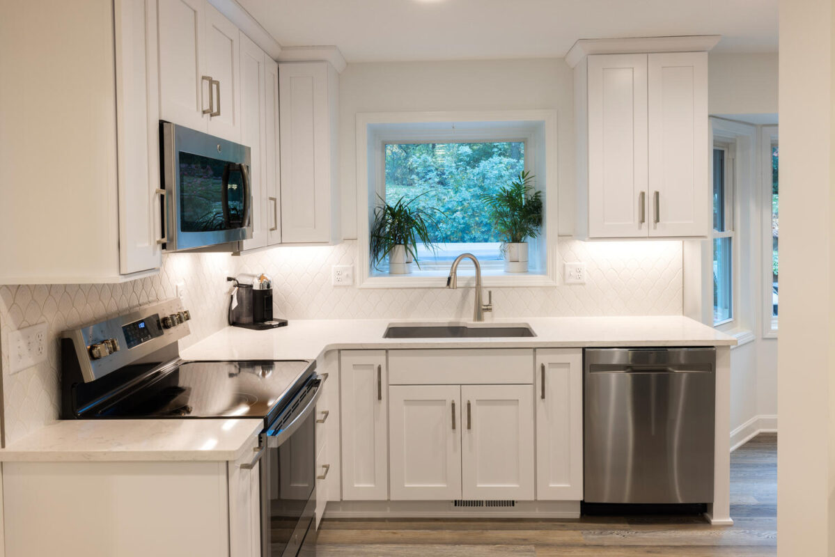 kitchen with white painted perimeter cabinets with view of dishwasher, oven, sink with window.