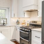 White painted kitchen cabinets with hood above stove