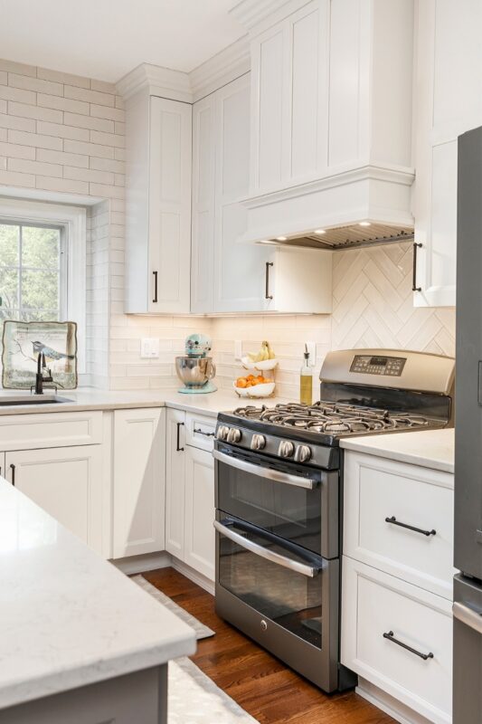White painted kitchen cabinets with hood above stove