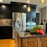 Kitchen with black painted and rustic natural cabinets showing stainless steel appliances