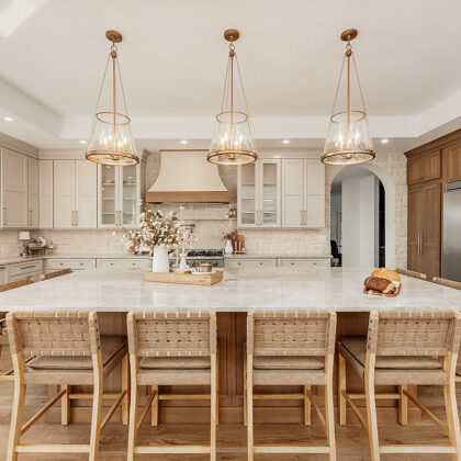 Painted and stained kitchen cabinets in a large open space with large windows.