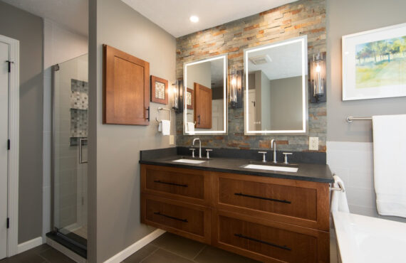 Floating vanity finished in Autumn stain near a large white tub.