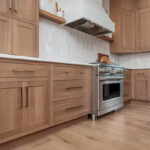Light brown-stained kitchen cabinets with a white painted wood hood