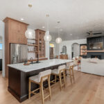Light brown-stained kitchen cabinets with a white painted wood hood and dark stained island cabinets