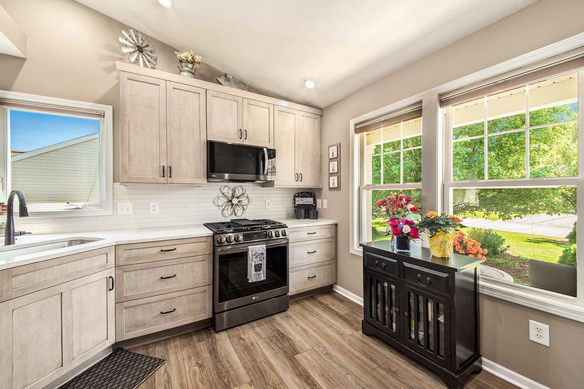 Light stained kitchen cabinets with black appliances.