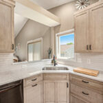 Light stained kitchen cabinets with black appliances.