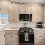 Light stained kitchen cabinets with black appliances.