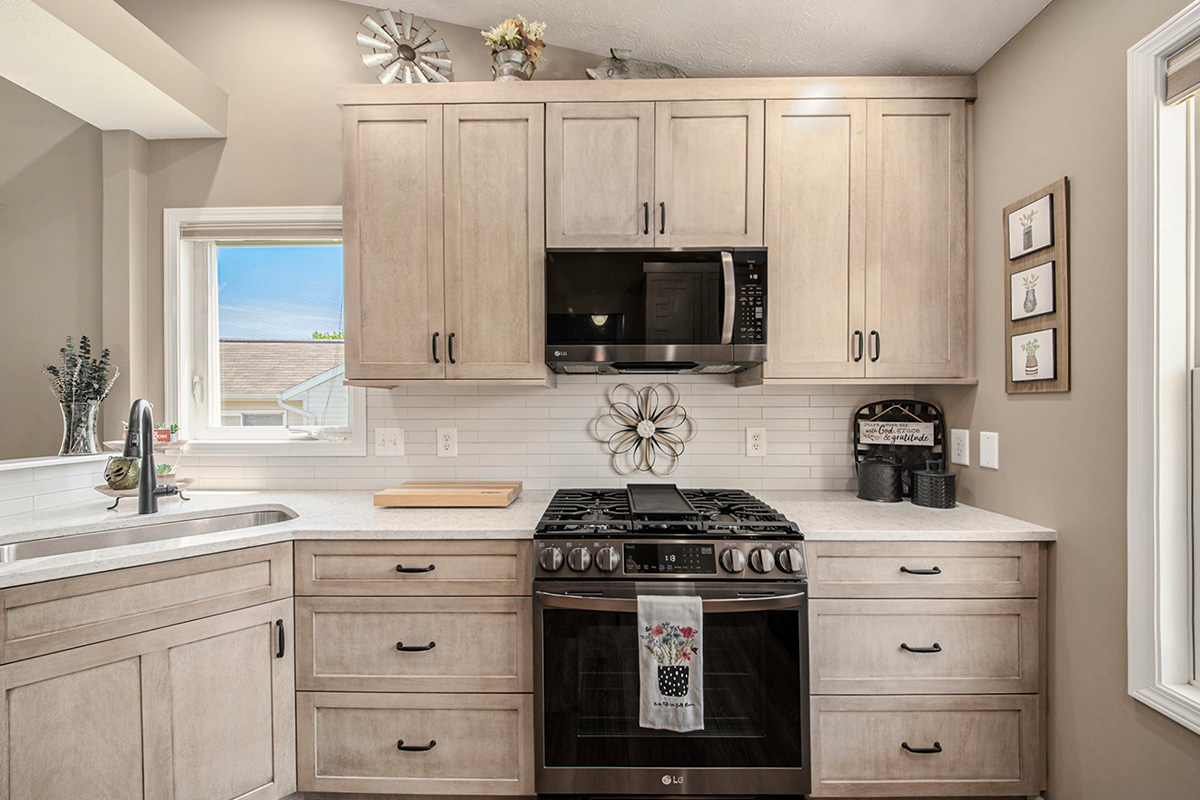 Light stained kitchen cabinets with black appliances.