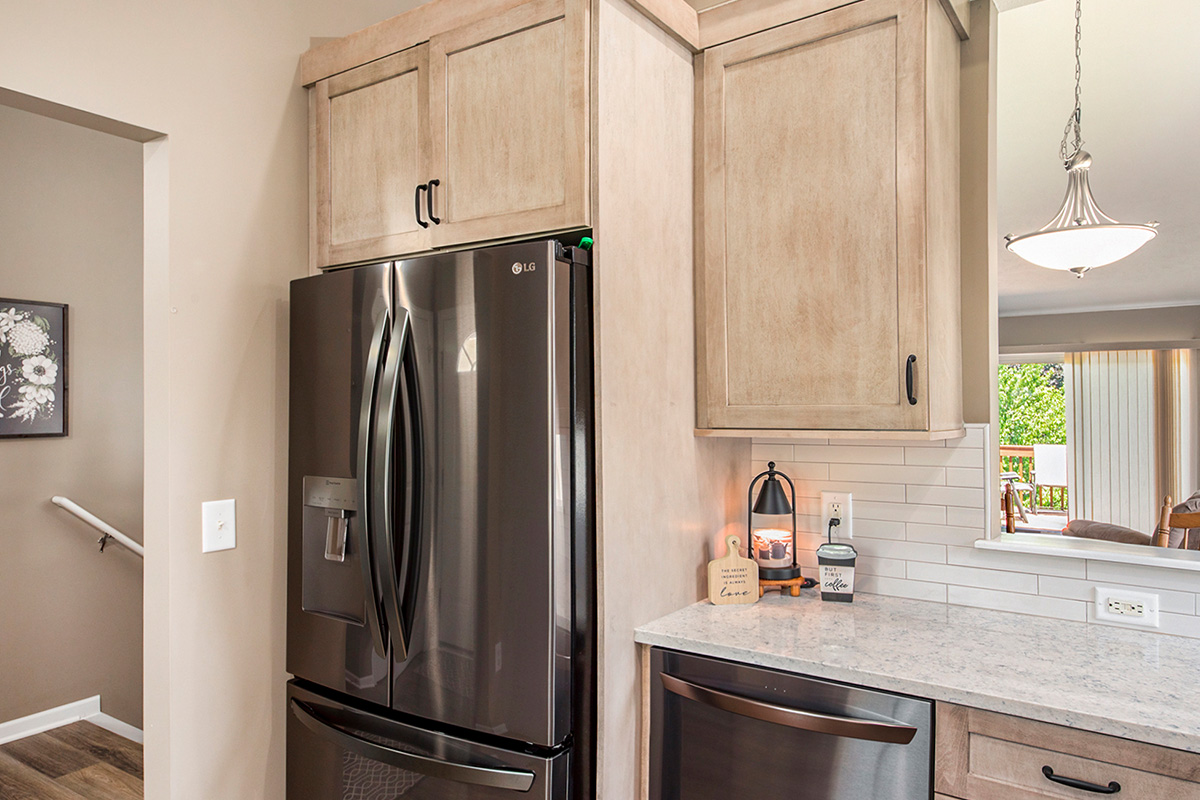 Light stained kitchen cabinets with black appliances.