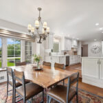 Dining room with table looking towards a white painted kitchen with wood floors